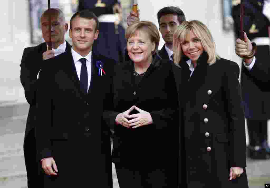 German Chancellor Angela Merkel, center, is greeted by French President Emmanuel Macron and his wife Brigitte Macron as she arrives at the Elysee Palace in Paris to participate in a World War I Commemoration Ceremony, Nov. 11, 2018. 